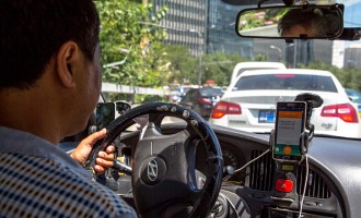A taxi driver is using Didi Dacha App while driving on the...