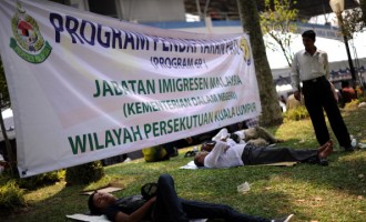 Foreign workers sleep under a banner