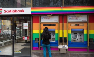 Pride rainbow flag:Woman operating Scotia bank automated