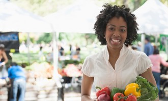 African American woman holding produce at farmers market