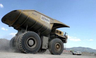 A large dump truck dwarfs a nearby vehicle 